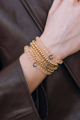 TELETIES spiral hair coils worn as bracelets on wrist, featuring gold and clear coil hair ties stacked together.
