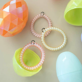 TELETIES spiral hair coils displayed with colorful Easter eggs on neutral background