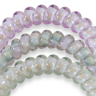 Three translucent spiral hair coils with iridescent shimmer and glitter accents displayed on black background.
