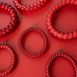 Red spiral hair coils arranged on matching red background showing coiled telephone cord style hair ties