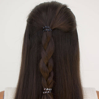 Back view of woman wearing small spiral hair coils in half-up hairstyle with braid