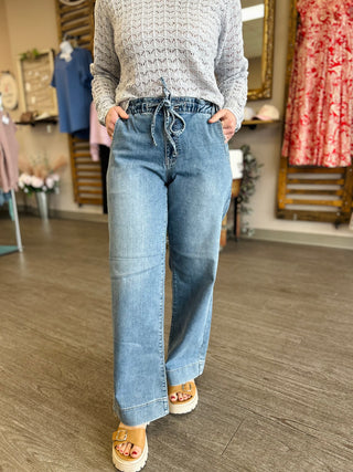 Woman wearing wide leg jeans with drawstring waist and light knit sweater in clothing store