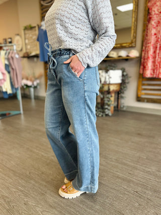 Woman wearing wide leg drawstring jeans with knit sweater and sandals in clothing store