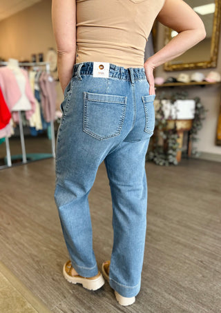 Person wearing wide leg jeans with drawstring waist and beige top in clothing store