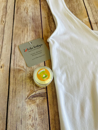 White tank top with small jar of SUDS stain remover and brand tag on wooden surface.