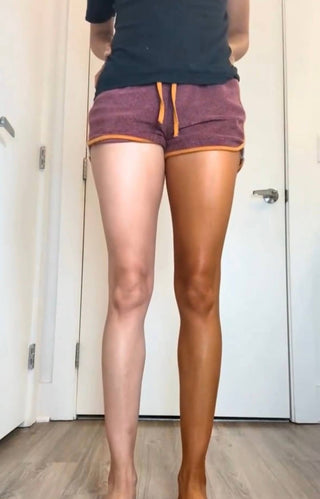 Person showing tanning results with one tanned leg and one untanned leg wearing purple shorts