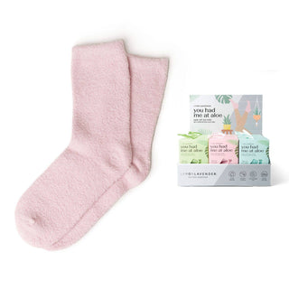 Pink fuzzy spa socks with moisturizing aloe vera next to retail packaging display box