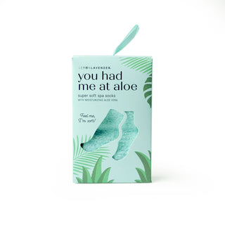 Green aloe vera spa socks packaging with tropical leaf design and product window display.