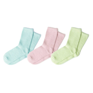 Three pairs of soft, fuzzy spa socks in pastel colors arranged on white background.