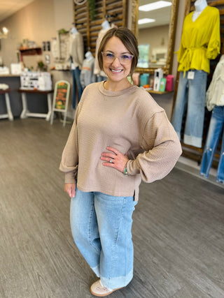 Woman wearing a relaxed-fit textured knit pullover top with balloon sleeves and side slits.