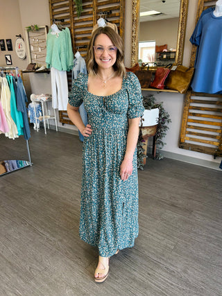 Woman wearing a floral puff sleeve maxi dress with smocked bodice in a boutique setting
