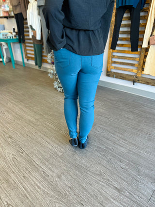 Person wearing bright blue skinny stretch pants with black ankle boots in casual indoor setting.