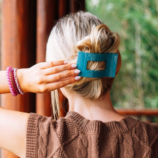 Woman securing an updo hairstyle with a TELETIES flat rectangle hair clip from behind.