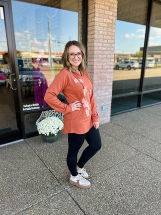 Woman wearing oversized floral print hoodie and leggings standing outside storefront entrance