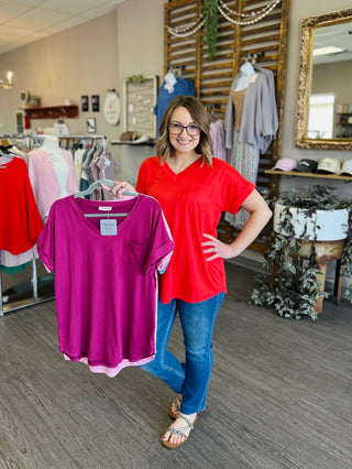 Woman in clothing store holding colorful pocket tee shirt, showcasing casual comfortable style options.