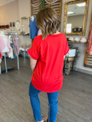 Woman wearing red oversized pocket tee with jeans, shown from behind in boutique setting
