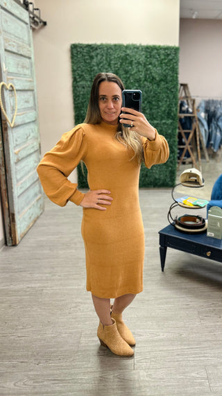 Woman wearing fitted knit sweater dress with long sleeves taking mirror selfie in boutique setting