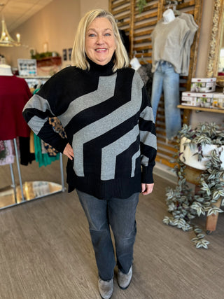 Woman wearing black and gray striped oversized sweater with jeans in clothing boutique setting