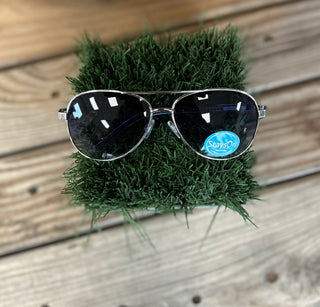 Aviator-style sunglasses with dark lenses and silver frames displayed on artificial grass against wooden decking.