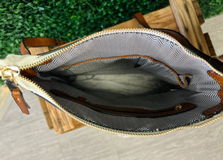 Open crossbody bag showing interior compartments with patterned lining and gold zipper details on wooden surface.
