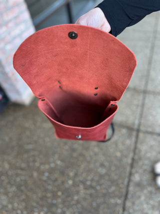 Hand holding red leather backpack showing interior compartment and quality craftsmanship details.