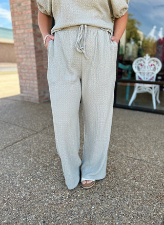 Woman wearing sage green knit wide-leg pants with drawstring waist and matching top outdoors