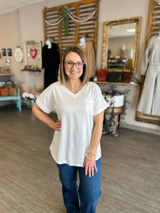 Woman wearing white v-neck pocket tee and jeans standing in boutique store interior