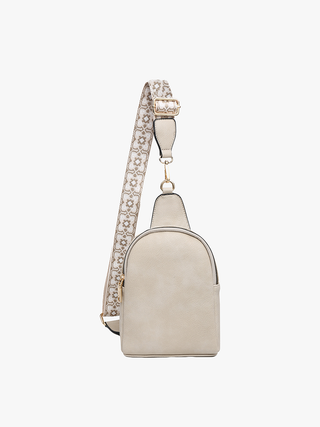 Beige sling bag with patterned adjustable strap and gold hardware against white background