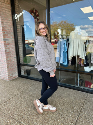 Woman wearing quilted quarter zip pullover standing outside clothing boutique storefront