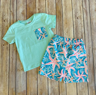 Light green t-shirt with tropical pocket and matching blue starfish print shorts on wooden background
