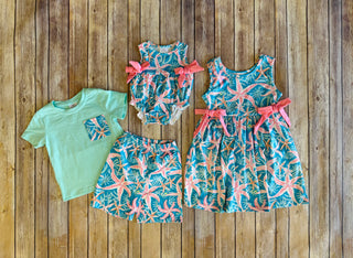 Tiny Tropics Boys Set featuring tropical print shorts, romper, dress and mint green tee on wooden background