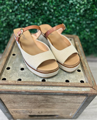 Corkys Treat Yourself platform wedge sandals with textured straps on rustic wooden crate display
