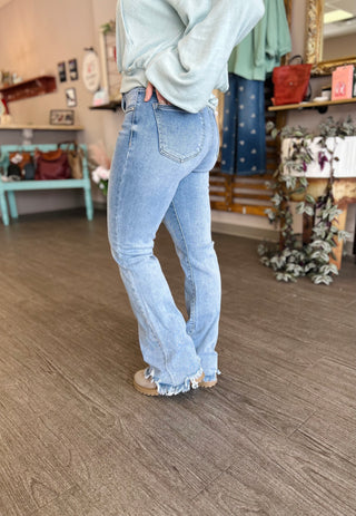 Person wearing Risen Tummy Control Midrise Frayed Flare jeans with light wash denim and frayed hem.