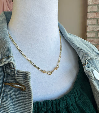Gold chain necklace with decorative clasp detail worn on white mannequin with denim jacket