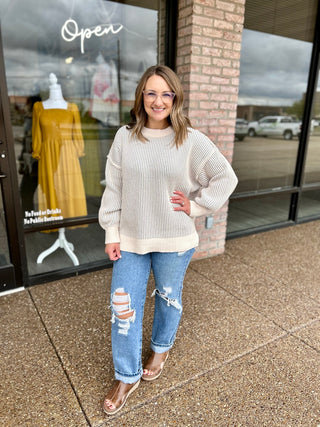Woman wearing a ribbed knit pullover sweater with puffed sleeves outside a boutique storefront.