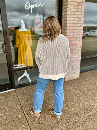 Woman wearing a ribbed two-tone oversized sweater paired with straight-leg jeans, back view.
