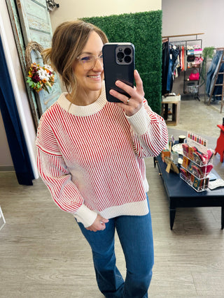 Woman wearing a striped knit pullover sweater with ribbed mock neck and cuffed sleeves.