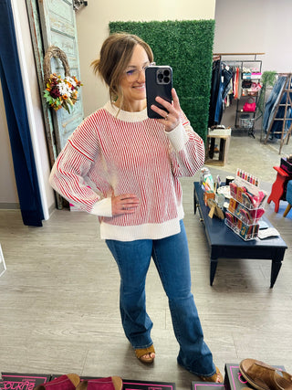 Woman wearing a striped knit pullover sweater with mock neck and balloon sleeves, paired with flare jeans.
