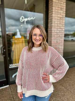 Woman wearing a ribbed striped crew neck pullover sweater with long sleeves, paired with jeans.