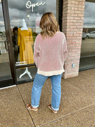 Woman wearing a striped two-tone ribbed knit sweater paired with light wash jeans and sandals.