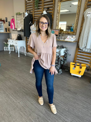 Woman wearing dark wash skinny jeans with button fly in boutique setting
