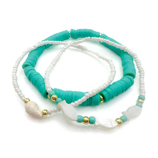 Turquoise and white beaded bracelets with gold accents and shell charms stacked together
