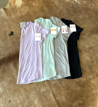 Four V-neck basic tees in different colors laid flat on cowhide with matching earring accessories