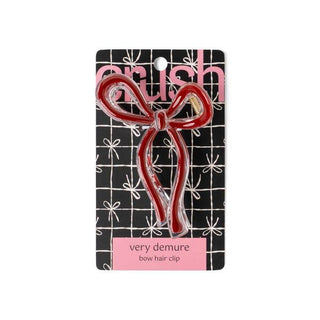Red bow-shaped hair clip on black packaging with white star pattern and pink branding