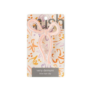 Pink bow-shaped hair clip on decorative floral packaging card with brand labeling.