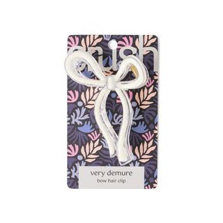 Clear acrylic bow-shaped hair clip on decorative floral packaging card with product branding.