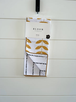 Bloom Towels dish towel with golden leaf pattern and black dotted design hanging on hook