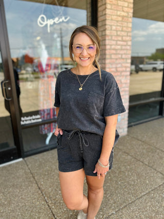 Woman wearing a casual matching crop top and drawstring shorts set with a chest pocket.
