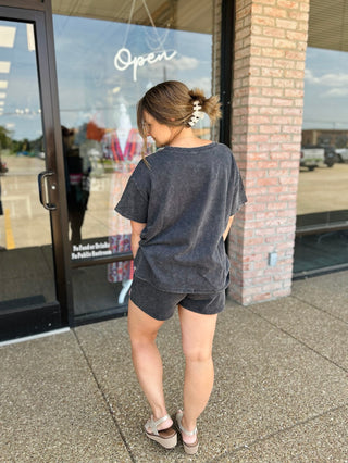 Woman modeling a matching washed oversized tee and shorts set with wedge sandals outdoors.