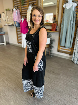Woman wearing black and white patterned crop overalls in clothing boutique store setting